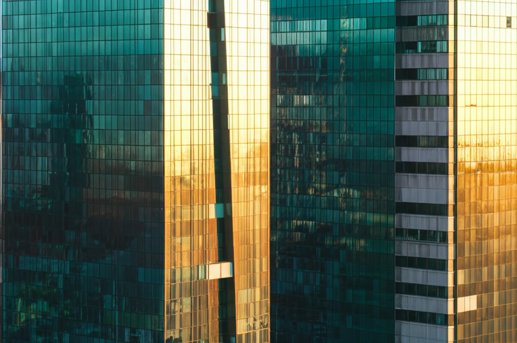 不動産投資2025年｜市場動向と会社員が取るべき戦略 - 東京都心の高層オフィスビル群と青空、ガラス張りの外壁に反射する光